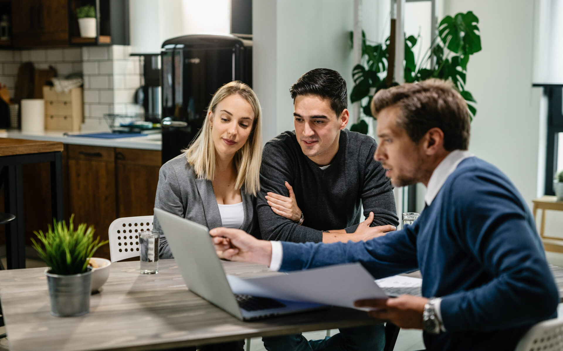 Smiling couple using a computer with their investment agent on a meeting.