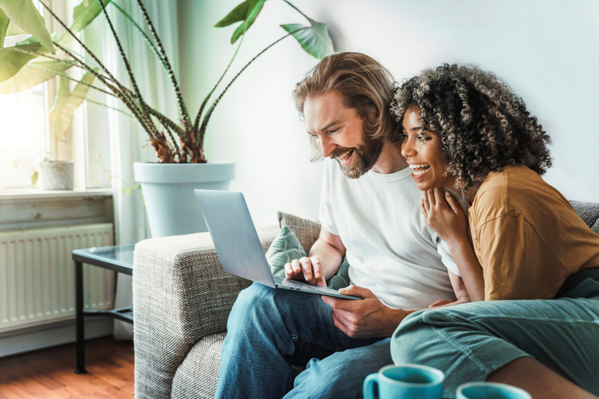 Multiracial young couple watching computer laptop sitting on the