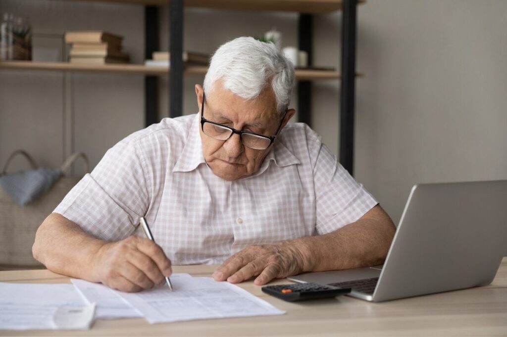 Elderly landlord checking paperwork and finances for UK rental portfolio review