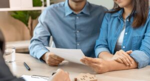 Couple sitting at a table reviewing a rental contract with an estate agent, symbolising landlord and tenant agreement