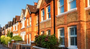 Red brick terraced houses with white window frames in a UK residential street, photographed in warm autumn evening light