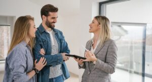 A smiling estate agent discussing a property sale with a couple during a home viewing, representing Hunters’ expert advice on preparing your home for sale in 2025.