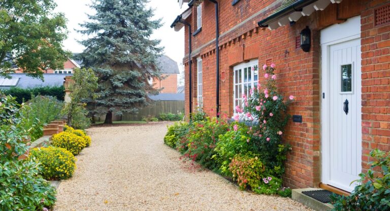 Exterior of a red brick UK home with a tidy gravel path and blooming garden, representing Hunters’ 2025 landlord guide on property repairs, inspections and compliance.