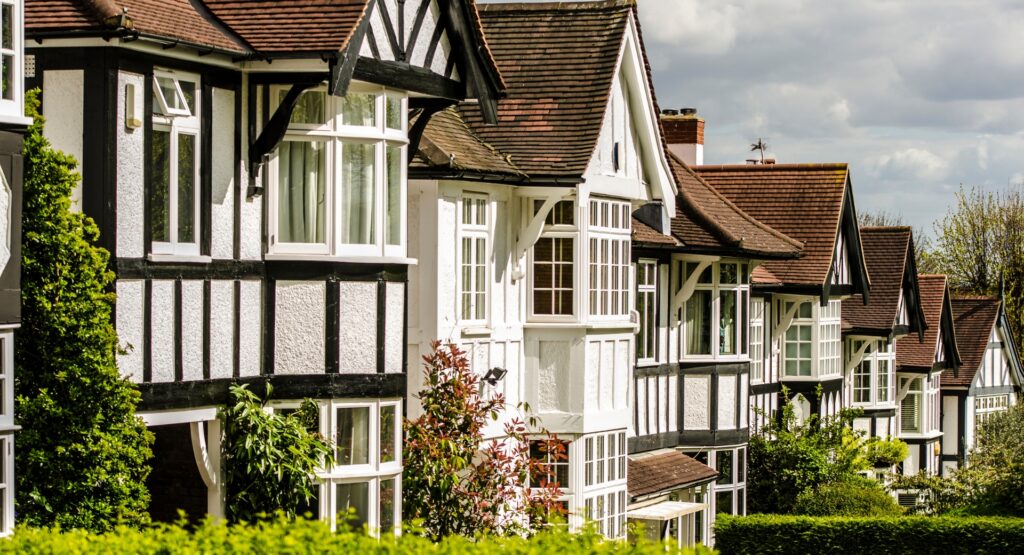 A row of traditional British period-style houses with white facades and timber detailing, representing UK suburban property – ideal for illustrating choosing the right estate agent.