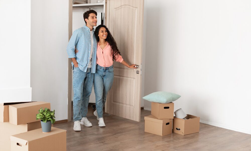 Couple walking into a bright new home with moving boxes on the floor, representing renters moving to Ebbsfleet Garden City and modern housing options in Northfleet and Gravesend.