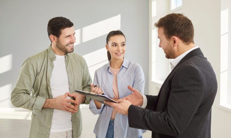Letting agent talking to a couple inside a bright property while reviewing tenancy documents.