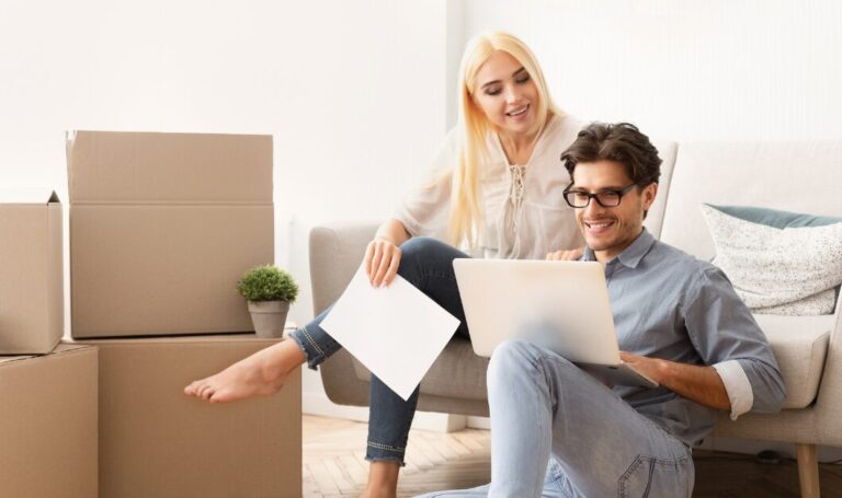 A couple reviewing documents on a laptop while sitting among moving boxes in a new home, representing confident property expansion and reduced risk under the UK Renters’ Rights Act 2025.