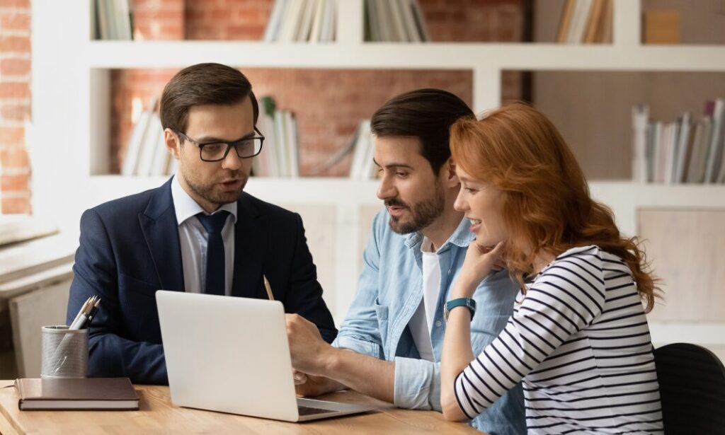 Professional advisor explaining tenancy changes to a couple during a meeting with a laptop.