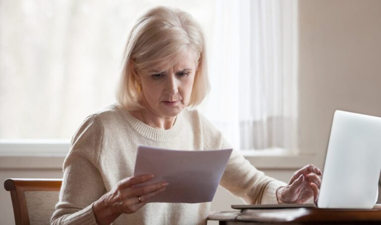 Landlord checking tenancy documents alongside rent records on a laptop