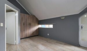 An empty, well maintained room with grey walls, tiled flooring, and built in wooden cupboards, representing a mortgage free home after inheritance and decisions about next steps.
