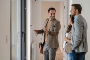 Estate agent guiding a couple through a modern home during a viewing, discussing features and potential value in Sutton Coldfield