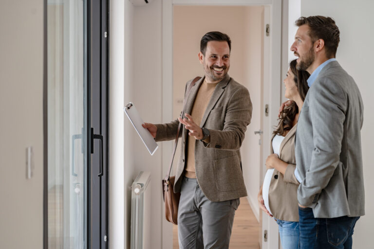 Estate agent guiding a couple through a modern home during a viewing, discussing features and potential value in Sutton Coldfield