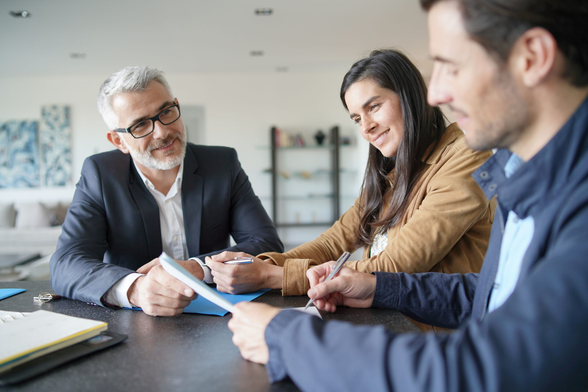 Landlords and property investors reviewing documents and discussing rental yield strategy at a table in a modern home setting
