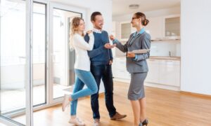 Estate agent handing keys to a couple inside a modern kitchen in Skipton