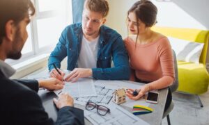 Couple reviewing property documents with an estate agent, representing how Dunstall Park homeowners can sell nearly new homes successfully in 2026