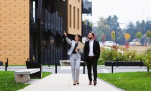 Property manager walking with a landlord outside modern Leeds apartments, illustrating selective licensing compliance support after the February 2026 deadline