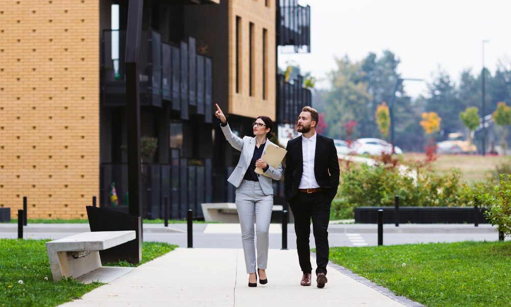 Property manager walking with a landlord outside modern Leeds apartments, illustrating selective licensing compliance support after the February 2026 deadline