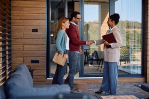 Landlord shaking hands with a letting agent outside a modern rental home, representing Rent Smart Wales licence renewal and compliance for Bridgend landlords in 2026