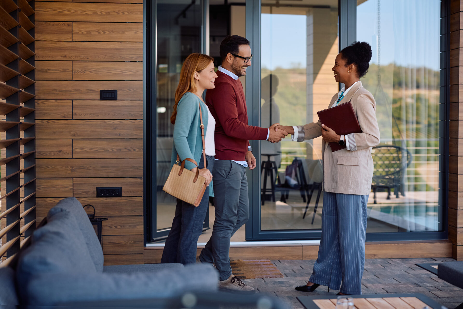 Landlord shaking hands with a letting agent outside a modern rental home, representing Rent Smart Wales licence renewal and compliance for Bridgend landlords in 2026