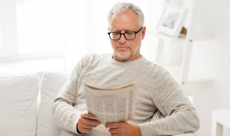 Landlord sitting at home reading documents while planning to sell a rental property with tenants in place