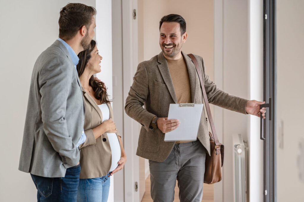 Estate agent welcoming a couple into a property during a viewing related to buy-to-let investment opportunities in Bridgend.