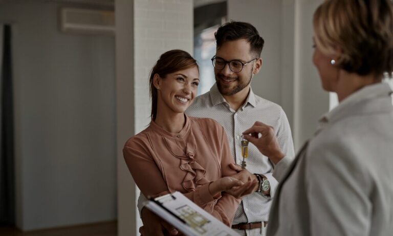 Estate agent giving house keys to a professional couple, representing corporate tenants and rental property success in Solihull.