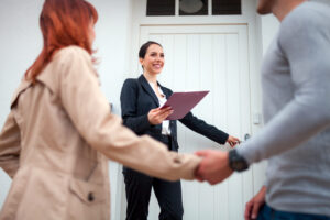 Estate agent welcoming a couple at the entrance of a rental property, reflecting landlord responsibilities under the Decent Homes Standard.