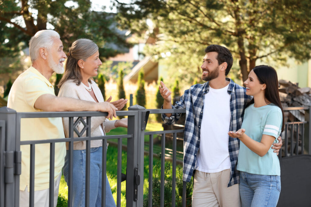 Young couple chatting with neighbours outside a home in Sutton Coldfield