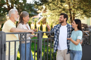 Young couple chatting with neighbours outside a home in Sutton Coldfield
