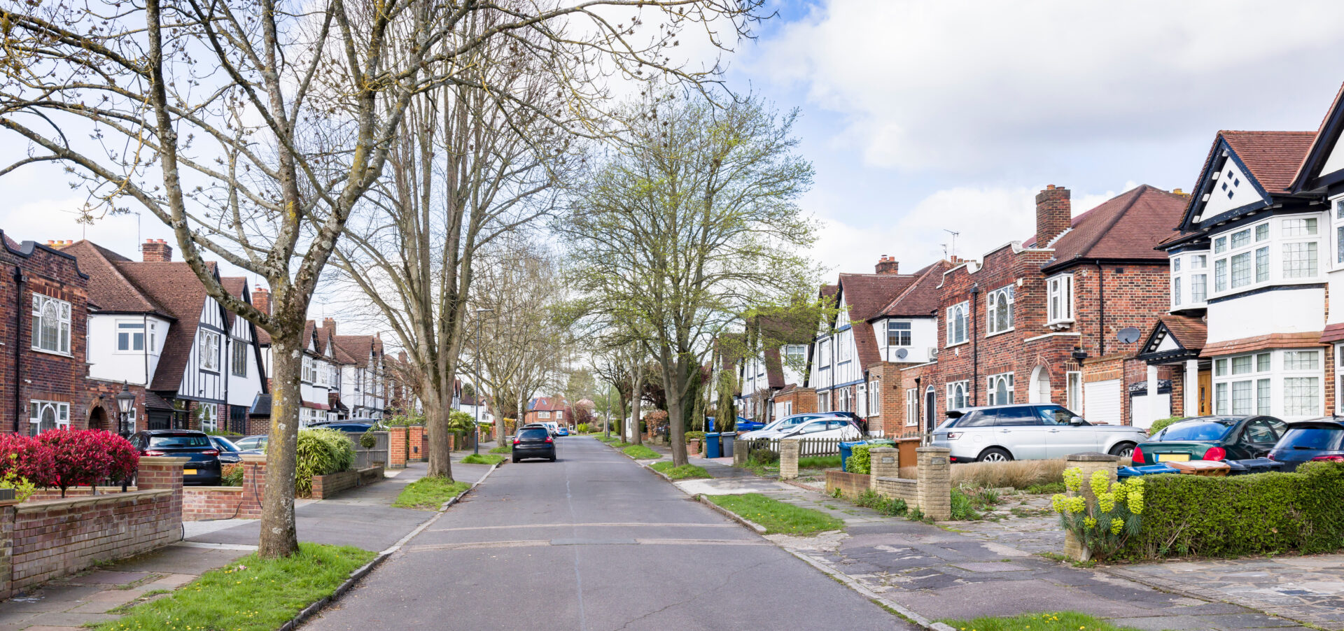 Tree-lined residential street with brick houses and parked cars in Bridgend