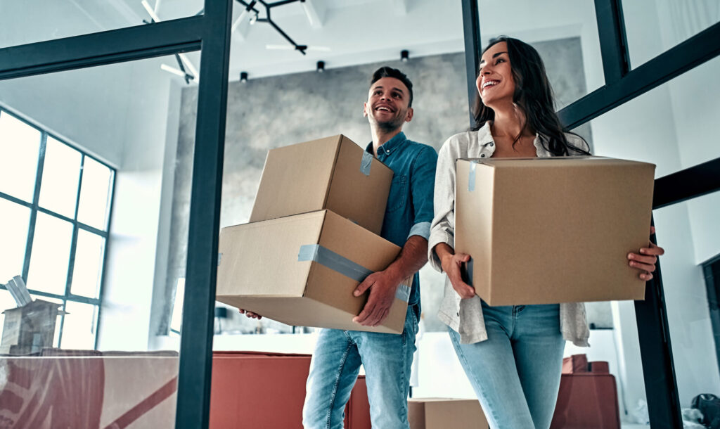 Couple carrying moving boxes into a new family home near Stanmore school catchment