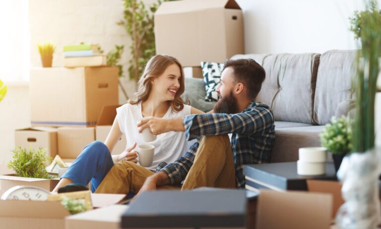 Couple sitting on the floor surrounded by moving boxes in a new family home