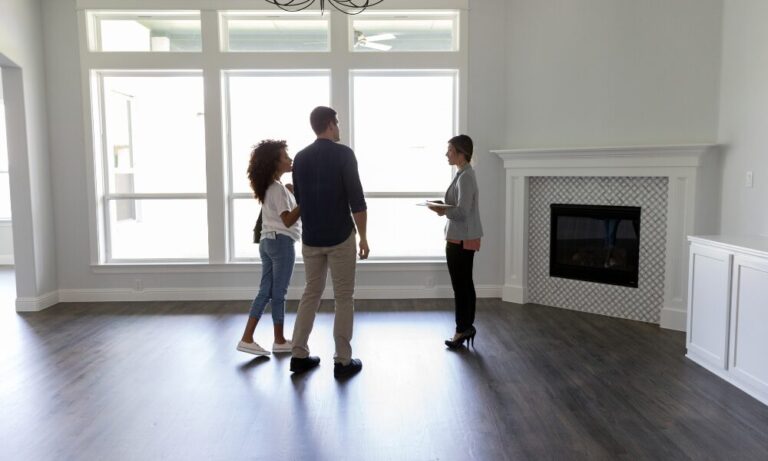 couple viewing a modern home interior with estate agent discussing property purchase