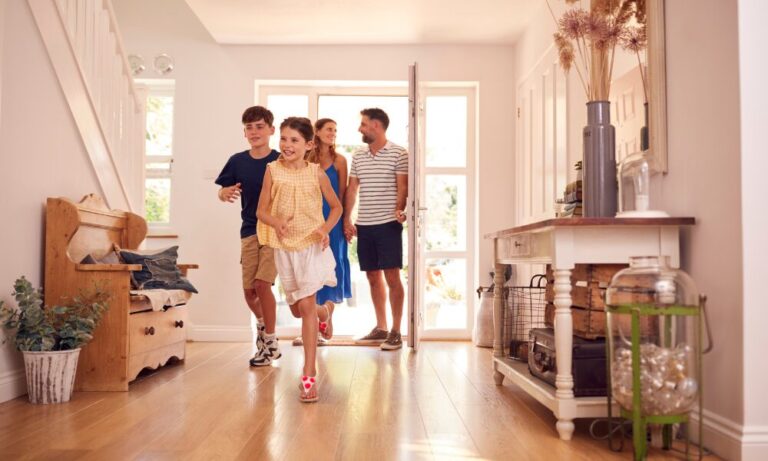 family entering new home together with children running inside bright hallway