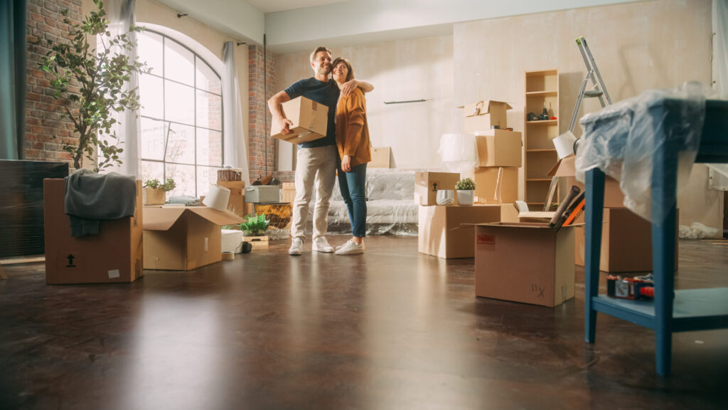 Couple standing in a new home surrounded by boxes after moving in