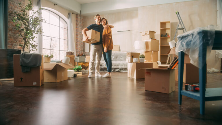 Couple standing in a new home surrounded by boxes after moving in
