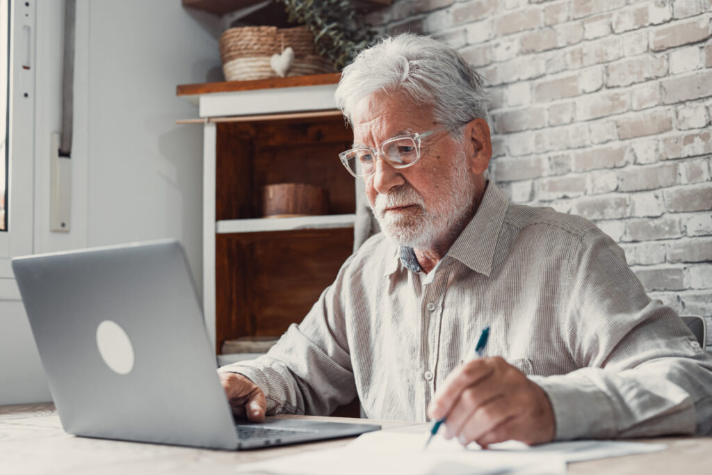 landlord reviewing rental property performance on laptop and taking notes at home