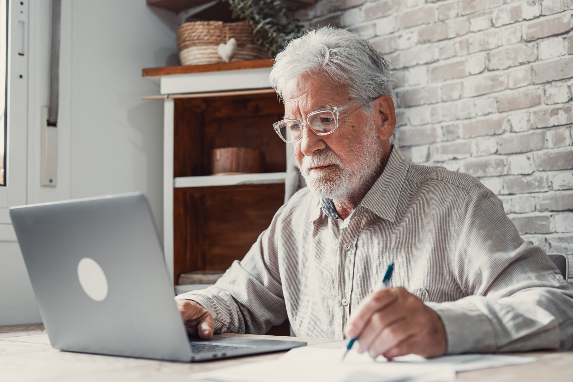 landlord reviewing rental property performance on laptop and taking notes at home