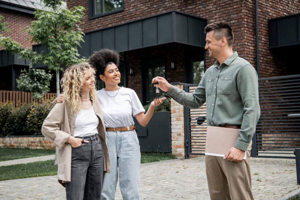estate agent handing house keys to first-time buyers outside modern home in Chesterfield