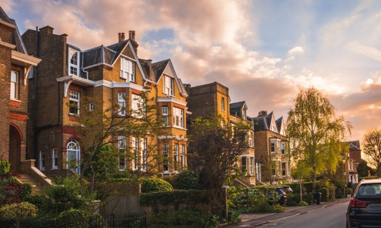 Large detached and semi-detached homes on a quiet residential street in the B93 area during sunset.