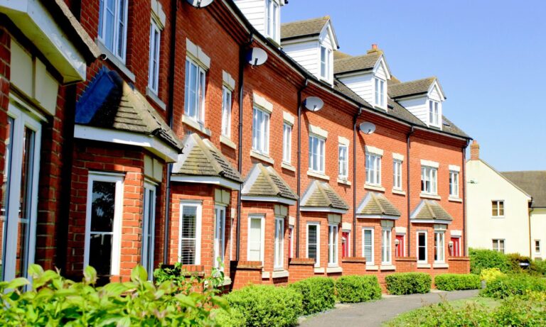 Row of modern red brick rental homes in Consett with landscaped greenery and residential walkways.