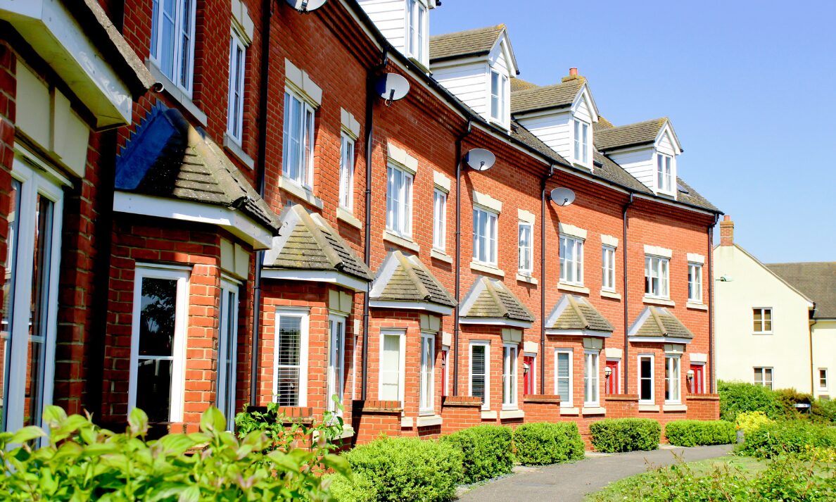 Row of modern red brick rental homes in Consett with landscaped greenery and residential walkways.