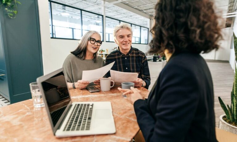 Older couple discussing property documents with an estate agent during a rental or investment consultation in Gravesend.