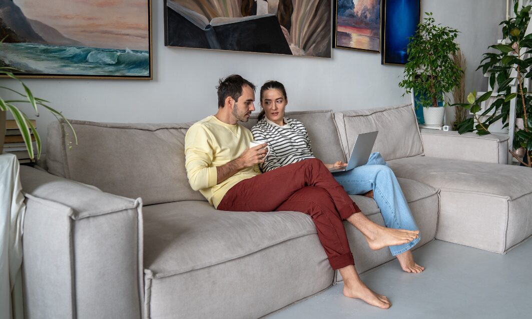 Landlords discussing rental property management services while reviewing documents on a laptop at home.