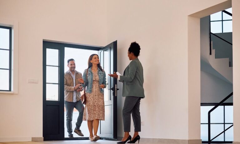 Estate agent welcoming a couple into a modern home in Bridgend during a property viewing