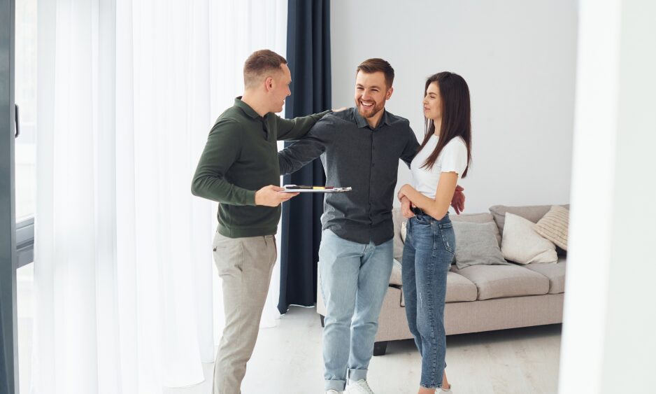 Estate agent showing a couple around a bright living room, representing first-time buyers looking for affordable homes in Annan.