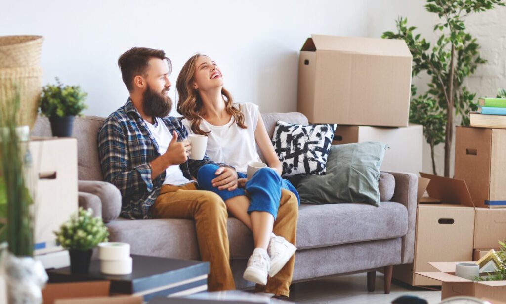 Couple sitting in their new home with moving boxes, representing the Belmont Circle HA3 area guide, local lifestyle, buying and renting advice.