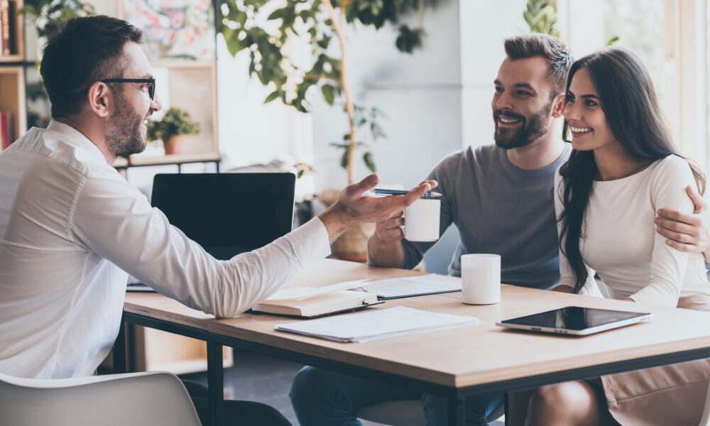 A property agent speaking with a smiling couple during a consultation, representing professional property management support for Southampton landlords looking to protect rental income and reduce tenant disputes.