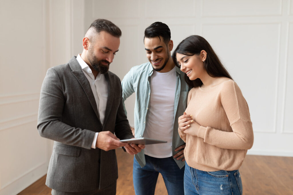 Estate agent showing property details to a couple, representing Lichfield house prices and buyer demand in WS14 and WS13.