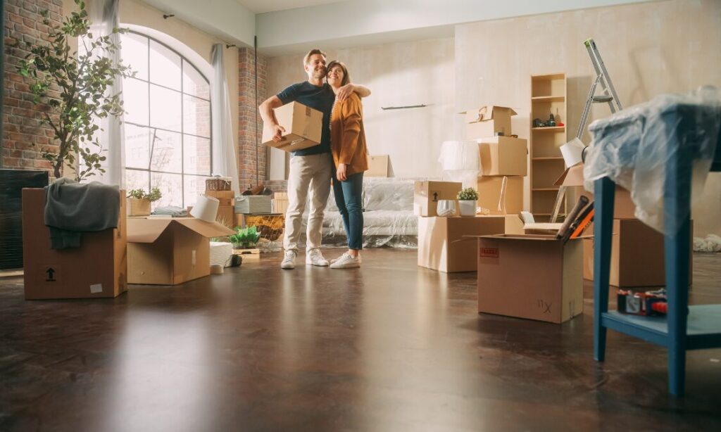 Couple standing among moving boxes inside a spacious luxury rental property in York, preparing to move into their new home.